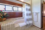 A large soaking tub with a shower. Windows can open to allow the trade winds to flow through the bathroom. 